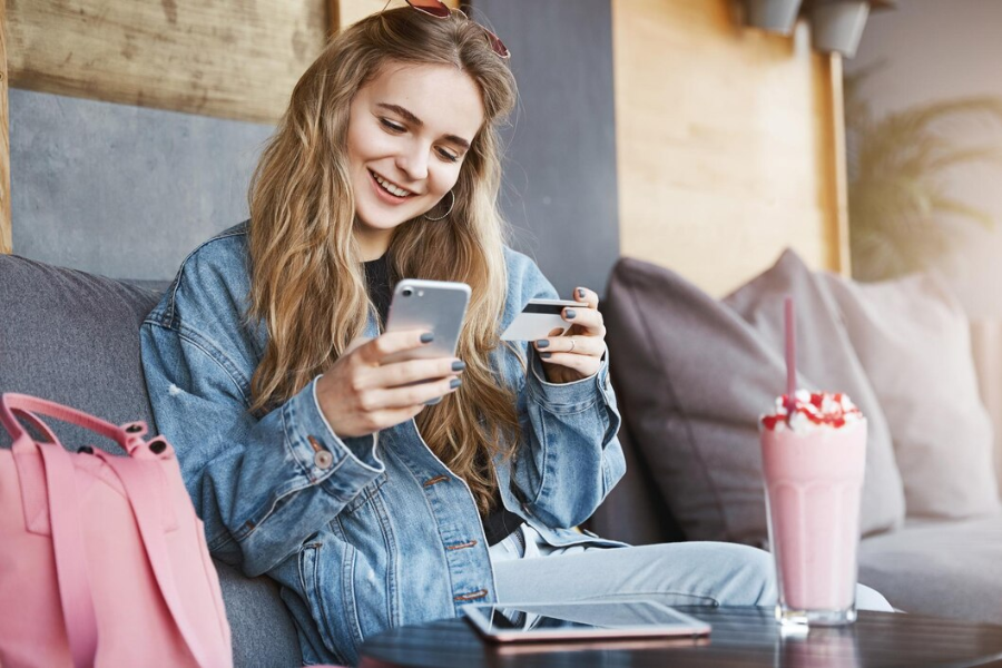 young person holding a smartphone and a-credit card