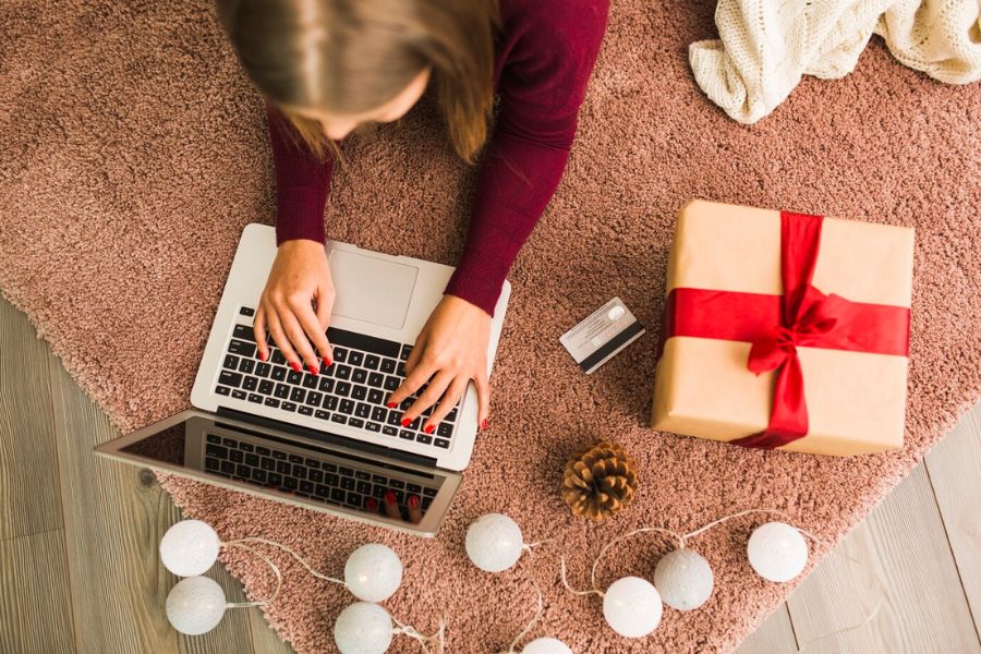 Woman online shopping with laptop and gift box