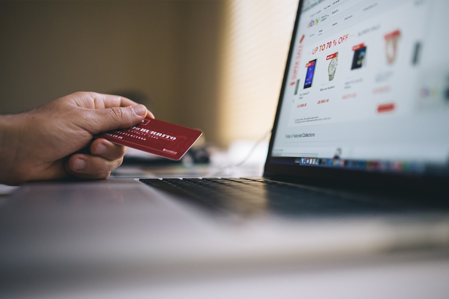 person holding credit card next to computer with an ecommerce site on the screen