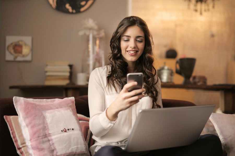 Person sitting down with a smartphone and a laptop on hand