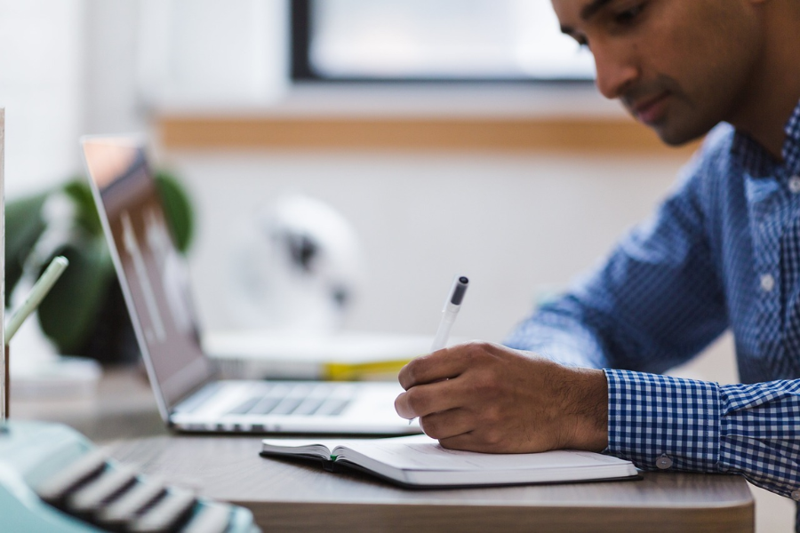 Man working on laptop and taking notes