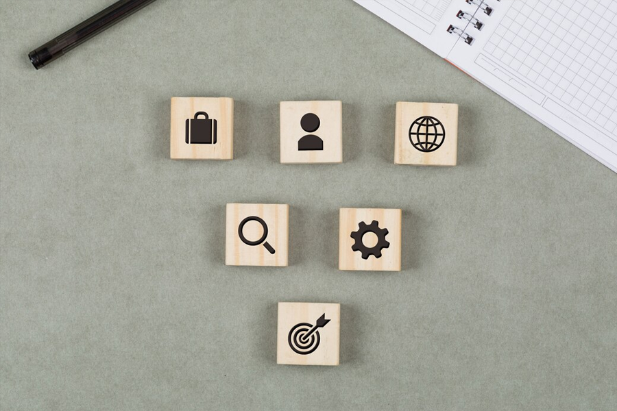 wooden cubes with business symbols (a briefcase, a target, a gear wheel) spread out on the table